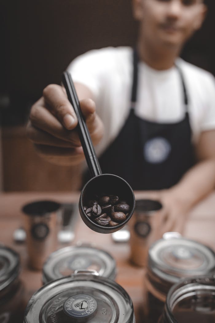 Close-up of coffee beans held by a barista in a café setting.